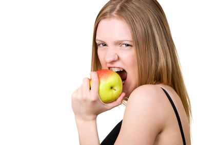 Beautiful young woman with brackets on teeth eating the apple